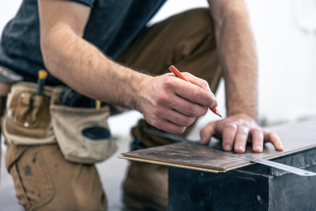Bodenleger der ein Stück Laminat schneidet